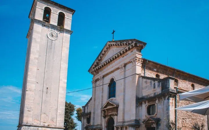 Pula Cathedral and bell tower under a clear blue sky.