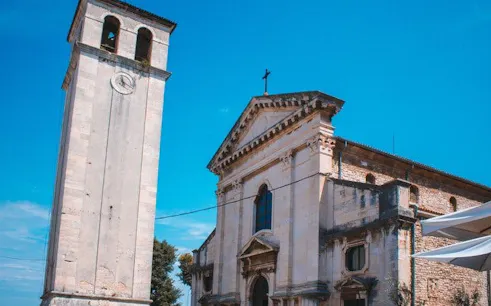 Pula Cathedral and bell tower under a clear blue sky.