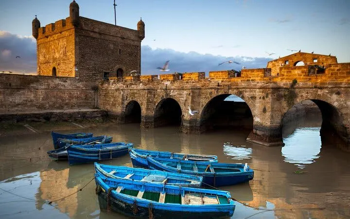 Essaouira harbor with blue fishing boats and historic stone fortress, Morocco.