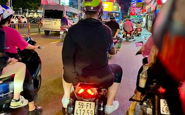Motorbikes navigating a busy street in Ho Chi Minh City during a back-alley food tour.