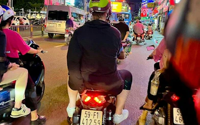 Motorbikes navigating a busy street in Ho Chi Minh City during a back-alley food tour.