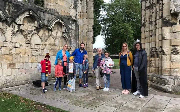 Group of tourists on a Harry Potter walking tour in York, standing by historic stone ruins.