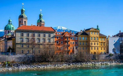 Colorful historic buildings along the Inn River with Alps in the background, Innsbruck.