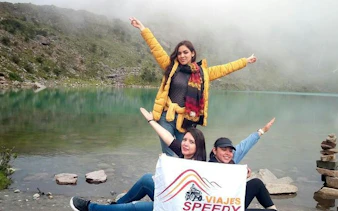 Trekkers posing by Humantay Lagoon with a tour banner, Cusco.