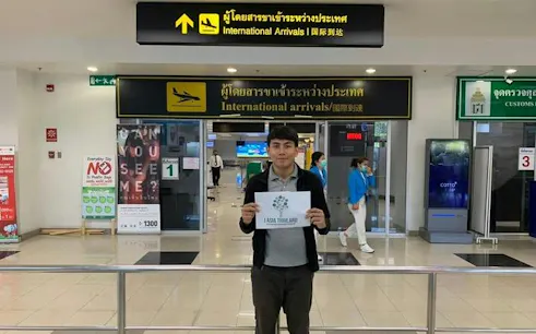 Chiang Mai Airport arrival area with a person holding a sign for private car transfers.