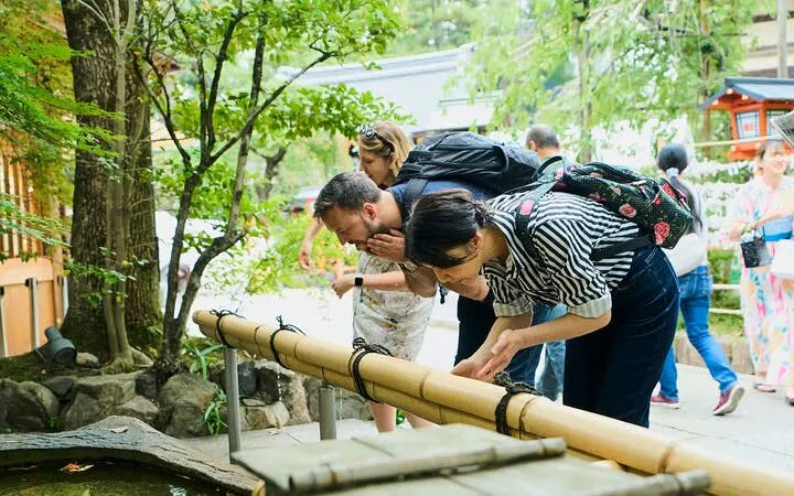 Visitors exploring a bamboo water feature in Kyoto's Gion district.