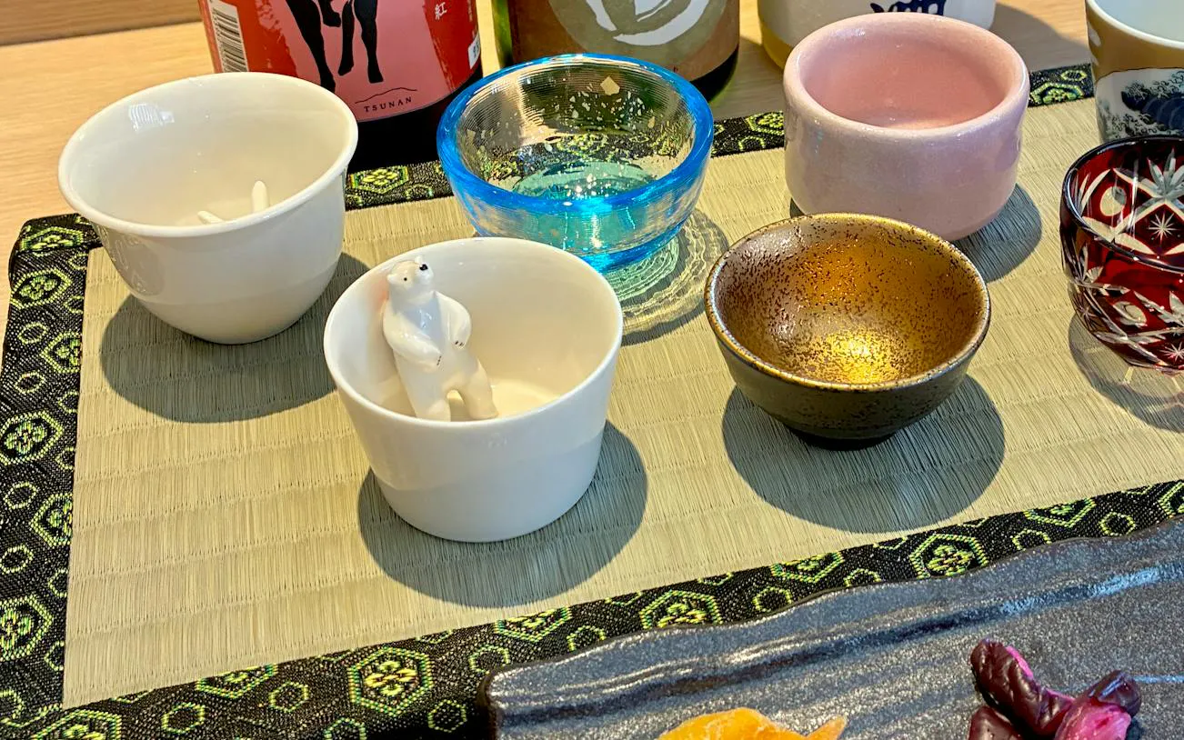Sake cups and bottles arranged for a tasting session in Kyoto.