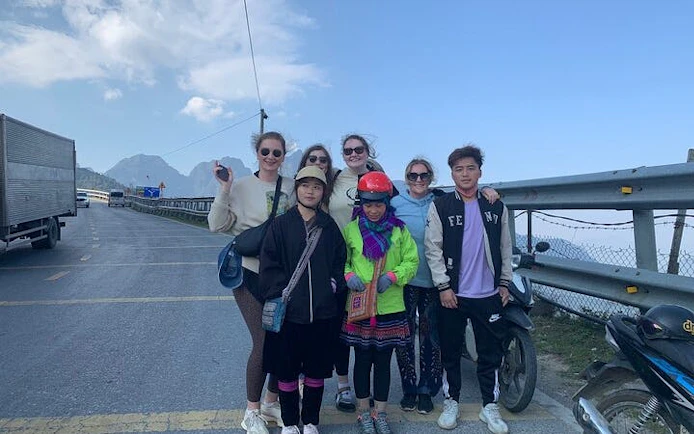 Group of tourists on a Sapa motorbike tour with scenic mountain view in the background.