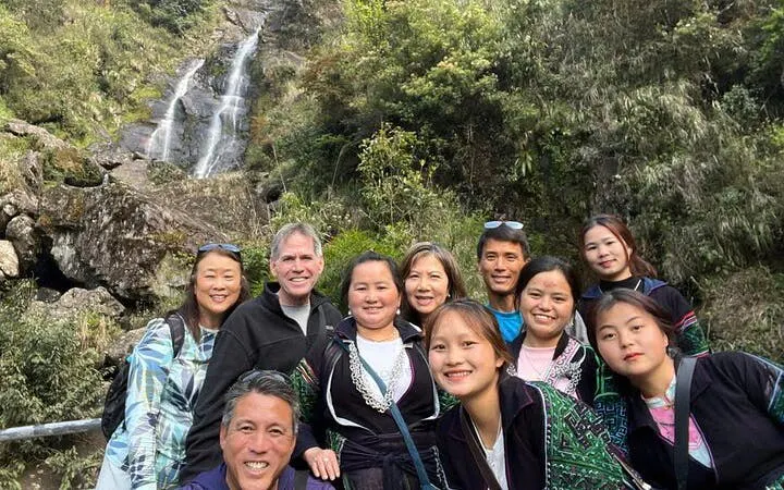 Group of tourists at a waterfall in Sapa, Vietnam during a motorbike tour of scenic villages.