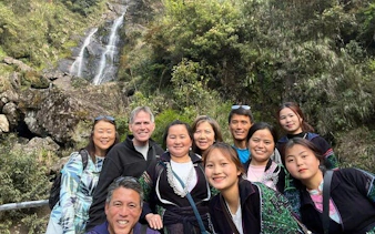Group of tourists at a waterfall in Sapa, Vietnam during a motorbike tour of scenic villages.