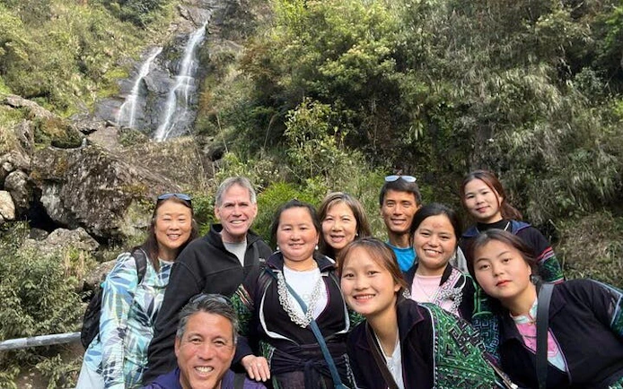 Group of tourists at a waterfall in Sapa, Vietnam during a motorbike tour of scenic villages.