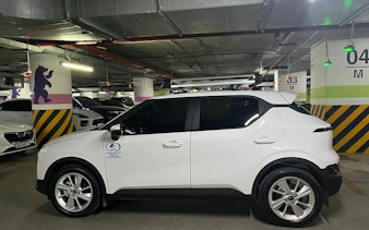 White car in a parking garage for private transfer from Sapa to Lào Cai Train Station.