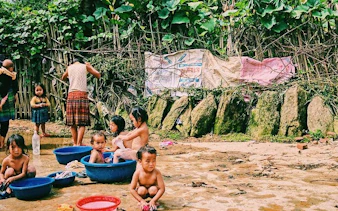 Children playing in water basins in Ta Van Village, Sapa, surrounded by lush greenery.