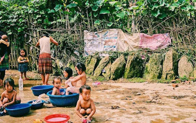Children playing in water basins in Ta Van Village, Sapa, surrounded by lush greenery.