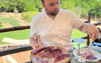 Man enjoying local charcuterie tasting in Val d'Orcia, Tuscany, during a private tour.