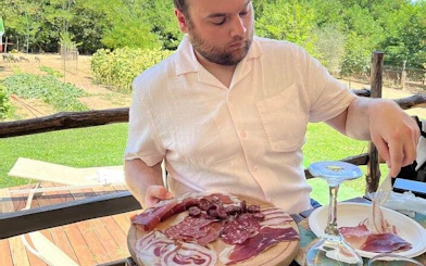 Man enjoying local charcuterie tasting in Val d'Orcia, Tuscany, during a private tour.