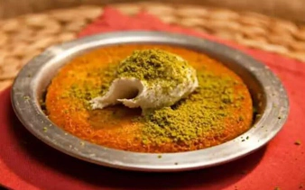 Künefe dessert with pistachios served on a metal plate in Turkey.
