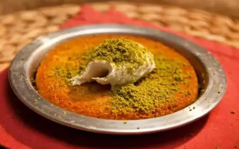 Künefe dessert with pistachios served on a metal plate in Turkey.