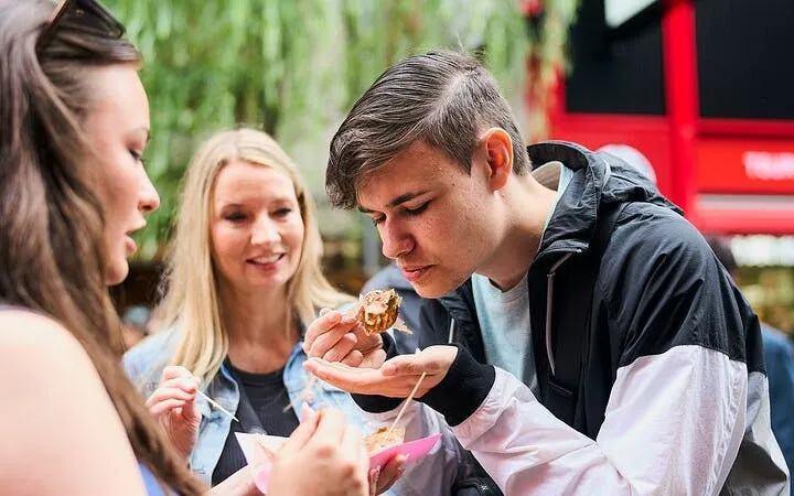 Tourists enjoying street food on an Osaka walking tour, exploring local markets and hidden spots.