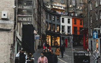 Edinburgh street with tourists near Grassmarket, featuring historic buildings and Harry Potter film locations.