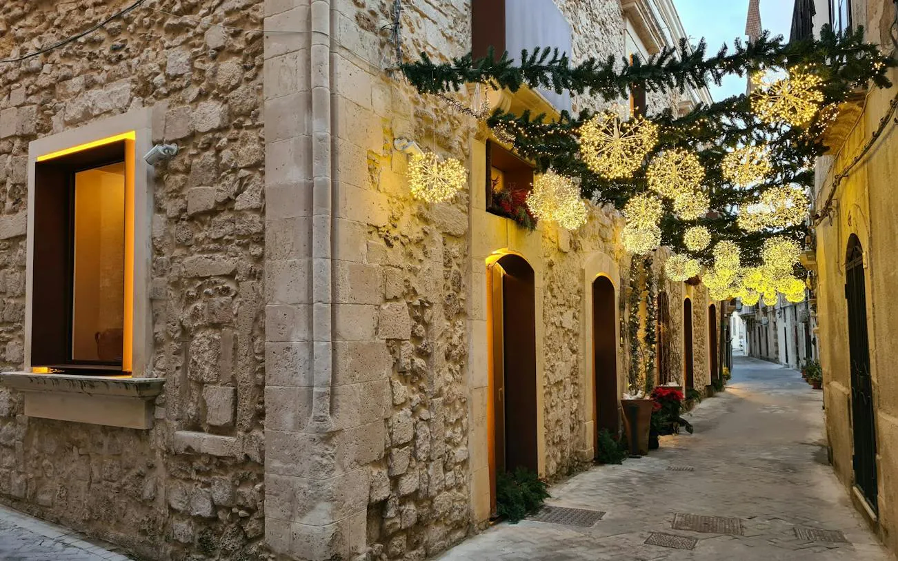 Narrow street in Ortigia Siracusa with festive lights and stone buildings.