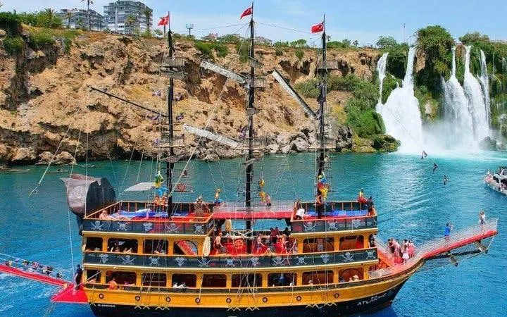 Pirate-themed boat near Lower Duden Waterfall in Antalya with tourists on deck.