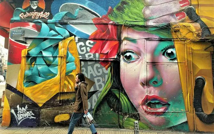 Street art mural with vibrant colors on a building in Athens, featuring a woman's face and abstract designs.
