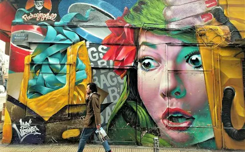 Street art mural with vibrant colors on a building in Athens, featuring a woman's face and abstract designs.
