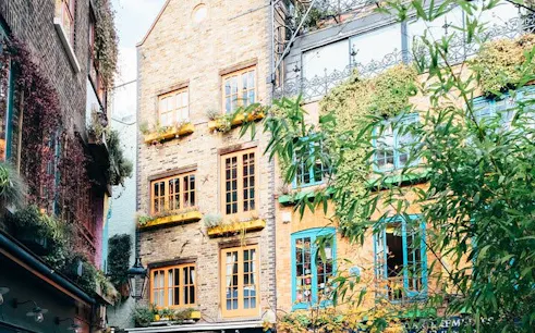 Historic London alleyway with colorful buildings and greenery on a guided walking tour.