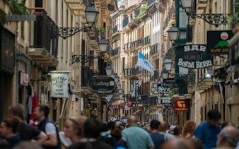 Crowded street in San Sebastian with shops and signs during a self-guided walking tour.