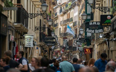 Crowded street in San Sebastian with shops and signs during a self-guided walking tour.