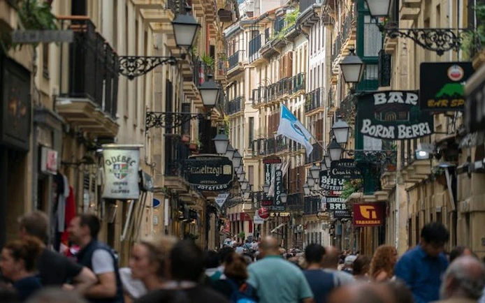 Crowded street in San Sebastian with shops and signs during a self-guided walking tour.