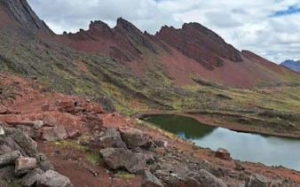Red Valley landscape with rocky terrain and lake, part of ATV tour and Rainbow Mountain hike, Cusco.