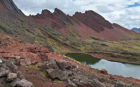Red Valley landscape with rocky terrain and lake, part of ATV tour and Rainbow Mountain hike, Cusco.