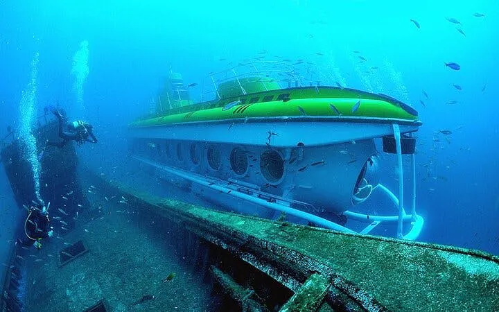 Submarine exploring underwater near shipwreck in Tenerife.