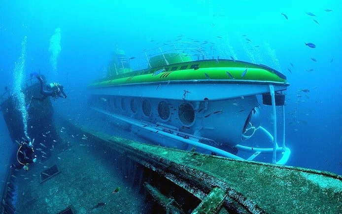 Submarine exploring underwater near shipwreck in Tenerife.