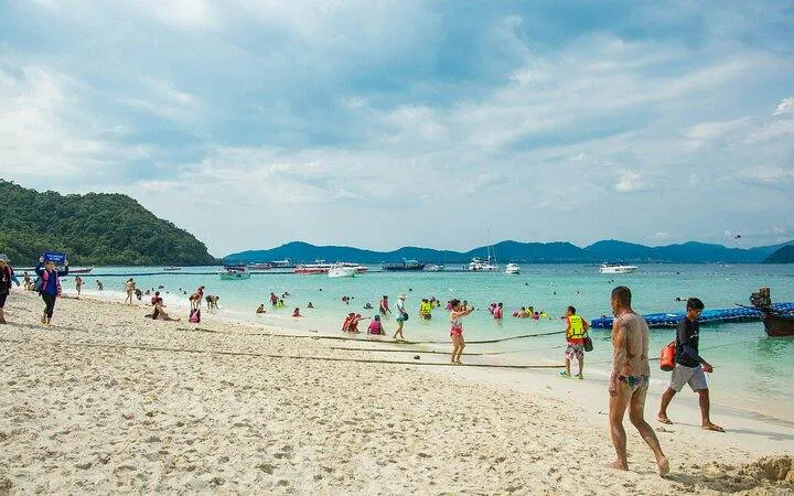 Tourists enjoying the beach and swimming at Banana Beach, Koh Hey, with boats in the background, Phuket.