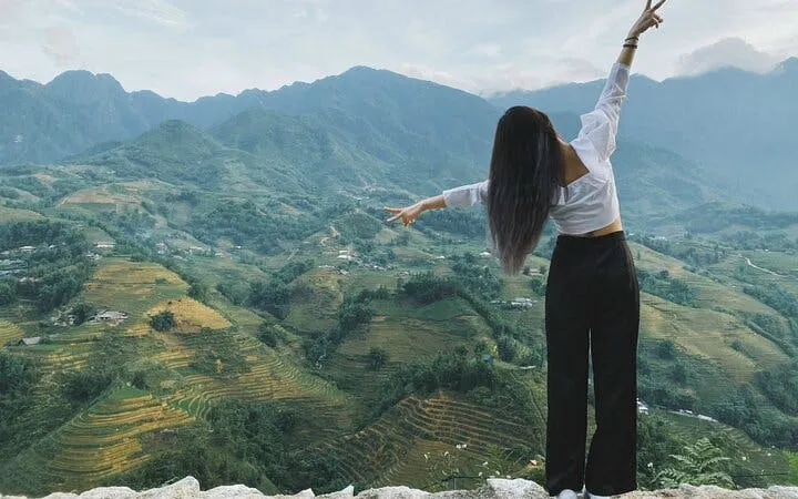 Sapa rice terraces and mountains with person enjoying the view during trekking tour.
