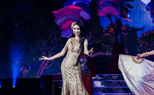 Performer on stage at Tiffany's Cabaret Show, Pattaya, with vibrant fans in the background.