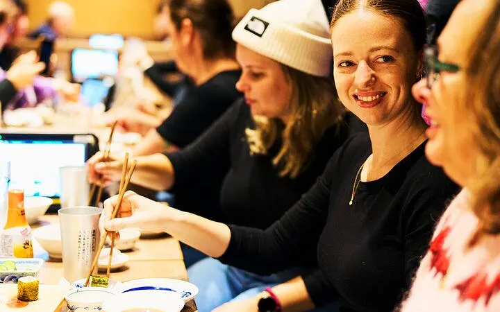 People enjoying a meal with chopsticks during a Shinjuku bar hopping tour in Tokyo.