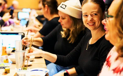 People enjoying a meal with chopsticks during a Shinjuku bar hopping tour in Tokyo.