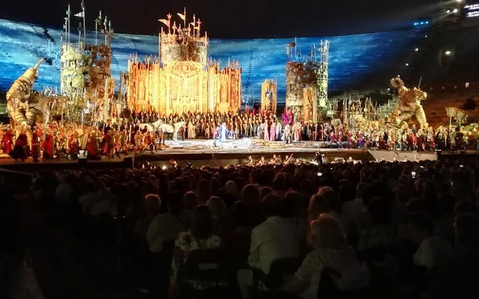 Opera performance at Arena di Verona with elaborate stage set and audience.