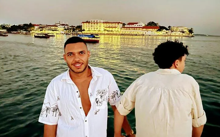 Two people on a semi-submarine cruise with Stone Town, Zanzibar in the background at sunset.