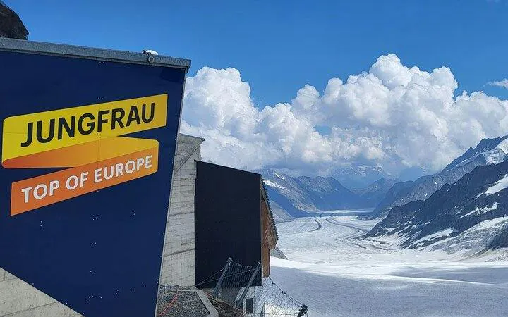 Jungfraujoch sign with view of Aletsch Glacier under cloudy sky, Switzerland.