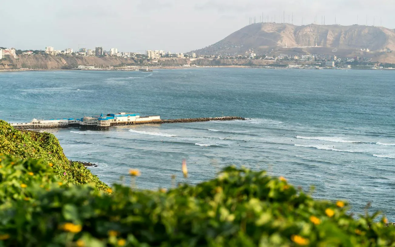 Coastal view of Lima with pier and cityscape, seen from Barranco on a self-guided audio tour.