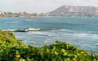 Coastal view of Lima with pier and cityscape, seen from Barranco on a self-guided audio tour.