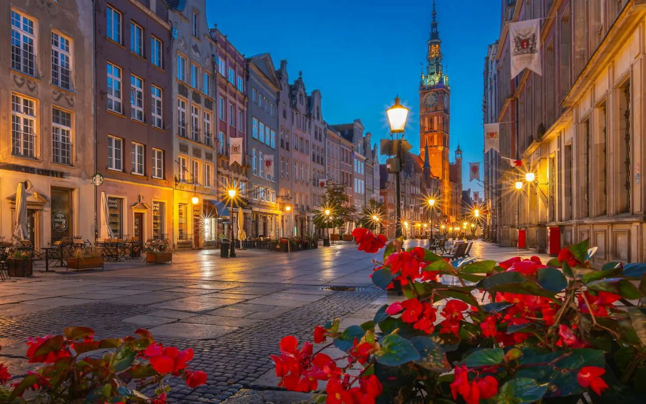 Gdansk Old Town street view with historic buildings and St. Mary's Church at dusk.