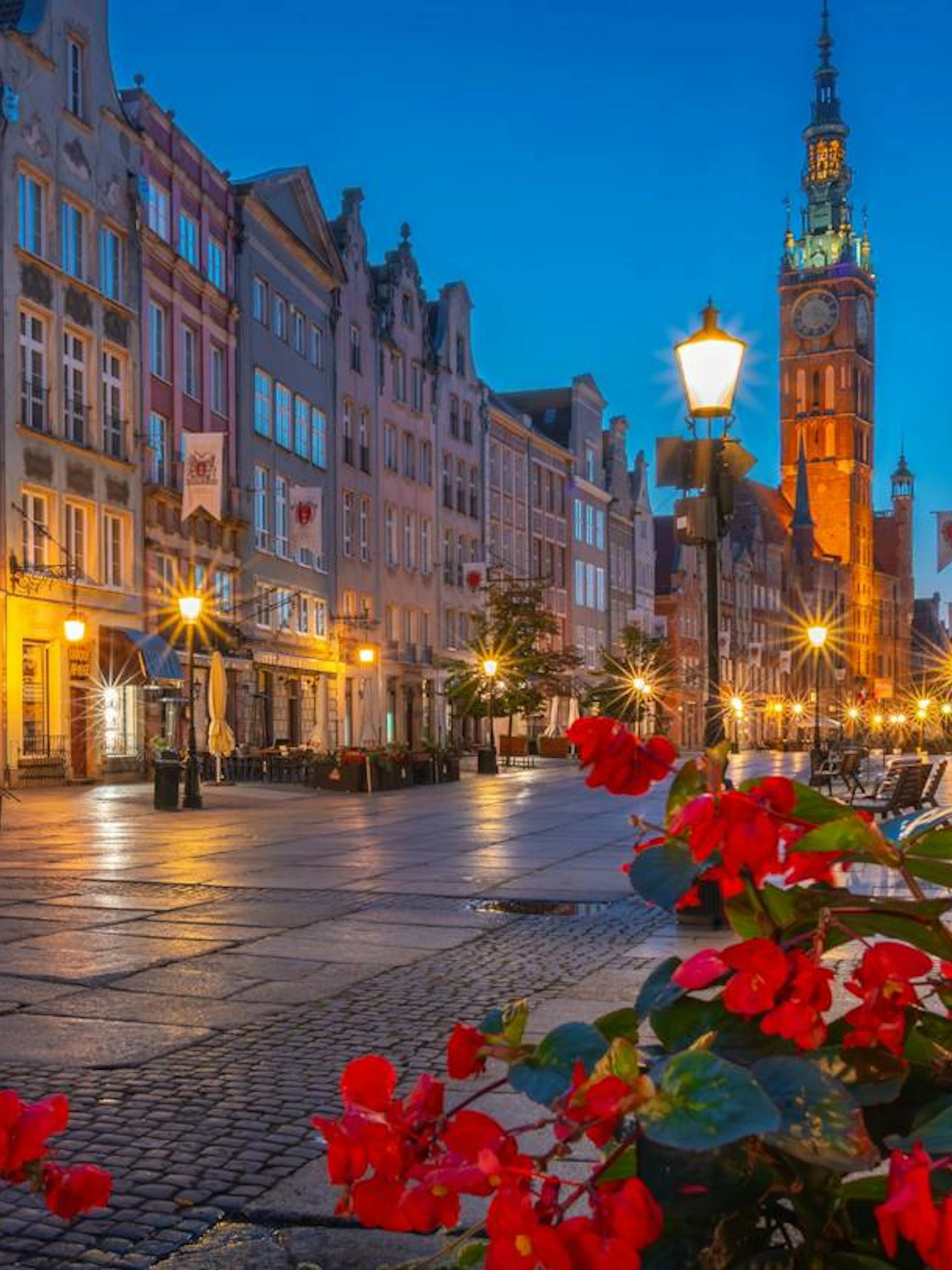 Gdansk Old Town street view with historic buildings and St. Mary's Church at dusk.