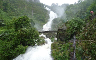 Silver Waterfall cascading with a bridge in lush greenery, part of the private car tour.