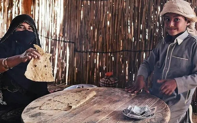 Local woman and child sharing traditional bread in a hut during Sharm El Sheikh desert safari.